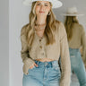Close up view of model wearing the Coming Back For More Cardigan which features taupe knit fabric, a collared neckline, tortoise buttons, and long balloon sleeves with a relaxed fit.