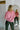 Back view of model wearing the Give Me A Reason Top, that features dark pink knit fabric, a henley neckline with gold buttons closures, side slits, dropped shoulders, and long balloon sleeves.