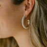 Close side view of model wearing the Lexington Pearl Hoops that feature large open gold hoops with small pearl beading.