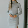 Close up view of model wearing the All Day Ribbed Dress which features grey ribbed fabric, slits on each side of the hem, turtleneck neckline, and long sleeves.