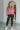 Full body front view of model wearing the Give Me A Reason Top, that features dark pink knit fabric, a henley neckline with gold buttons closures, side slits, dropped shoulders, and long balloon sleeves.