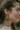 Close side view of model wearing the Hopeless Romantic Earrings that feature open gold teardrops with blue floral stones.