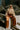 Full body view of model wearing the Need More Time Satin Pants which features copper silk fabric, two front pockets, a zip and hook closure, a half elastic waistband, and wide legs.