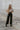 Full body view of model wearing the My Eyes On You Bodysuit which features cream fabric, ruffle detailing, lettuce hem, square neckline, short puff sleeves with elastic band and thong bottom with button closures.