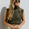 Front view of model wearing the Over It Sweater Vest that has dark green knit fabric with cable knit details, a turtleneck neckline, and a sleeveless body.