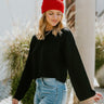 Front view of model wearing the Love Always Sweater in Black that has black knit fabric, a cropped waist, a round neckline, dropped shoulders, long sleeves with a relaxed fit