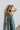 Upper front view of model wearing the One Way Ticket Overalls that feature dusty blue corduroy fabric, wide legs, one front pocket, two back pockets and button strap closures.