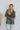 Front view of model wearing the True Icon Top that has black and silver plaid sheer fabric, a button-up front with a collared neckline, lettuce trim on the hem, and long sleeves with lettuce trim wrists. Styled buttoned up