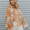 Front view of model wearing the Turn Back Time Top that has cream sheer fabric with mustard and brown pattern details, fabric covered buttons, a collared neckline, and long balloon sleeves with smocked wrists