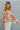 Side view of model wearing the Turn Back Time Top that has cream sheer fabric with mustard and brown pattern details, fabric covered buttons, a collared neckline, and long balloon sleeves with smocked wrists