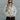 Front view of model wearing The In Bloom Teddy Jacket that has white teddy fabric with an olive flower pattern, a quarter zip closure with a collar, a cropped waist with a drawstring hem, and long sleeves.