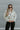 Front view of model wearing The In Bloom Teddy Jacket that has white teddy fabric with an olive flower pattern, a quarter zip closure with a collar, a cropped waist with a drawstring hem, and long sleeves.