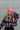 Front view of model wearing the Summit Beanie in Pink that features pink knit fabric, folded trim with a "C.C." emblem, and a faux fur pompom.