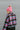 Side view of model wearing the Summit Beanie in Pink that features pink knit fabric, folded trim with a "C.C." emblem, and a faux fur pompom.