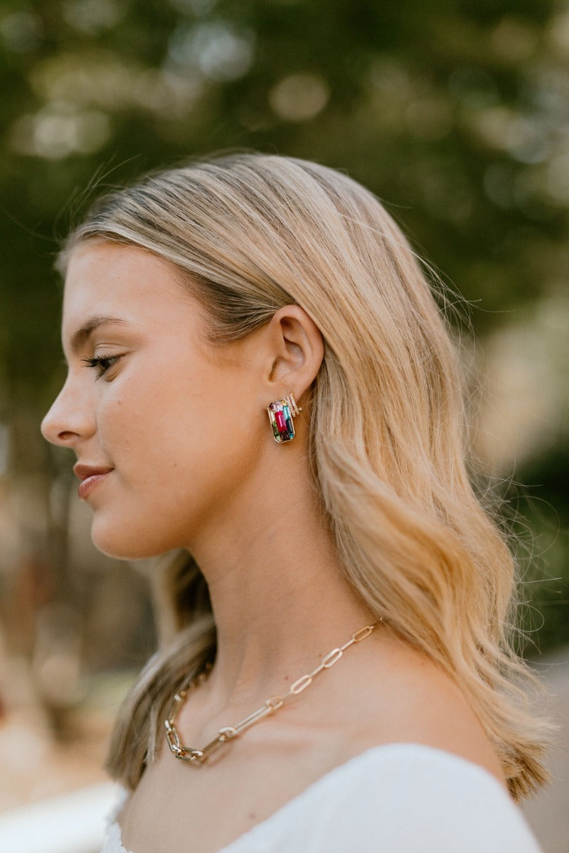 Side view of model wearing the Fairytale Ending Earrings that feature multi-colored stones in a gold rectangle on post backs.