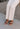 Image shows model wearing the Beach by Matisse Amalia Flat Sandal in Tan which feature light brown braided upper, two straps, slide-on style and flat sole. 