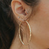 Close view of model wearing the On Your Own Hoop Earrings in Gold that feature large closed gold hoops with a hammered design.