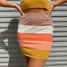 Frontal view of the Day Dreamer Skirt that features a stretchy knit material, a thick waist band, a multi-colored thick stripe pattern, and a mini length.