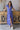 Front view of model wearing the Summertime Blues Maxi Dress that features royal blue fabric with a white floral print, maxi length, a slit on the side, a front tie closure, a surplice neckline and short sleeves