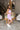 Side view of model wearing the Out And About Dress In Lavender which features lavender knit fabric, ruched side details, midi length, lavender lining, a round neckline and a sleeveless design.