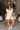 Full body view of model wearing the Modern Day Ruffle Romper which features cream fabric, pockets on each side, front zipper closure, square neckline, ruffle straps, elastic band in the back and sleeveless.