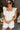 Front view of model wearing the Modern Day Ruffle Romper which features cream fabric, pockets on each side, front zipper closure, square neckline, ruffle straps, elastic band in the back and sleeveless.