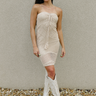 Full body view of model wearing the Boardwalk Views Dress which features tan open knit fabric, mini length, tan lining, strapless and drawstring tie upper.
