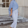 Full body view of model wearing the Rebecca White Denim Fray Straight Leg Jeans which features white denim fabric, front zipper with button closure, two front pockets, two back pockets, belt loops, high rise and straight pant legs with fray hem.