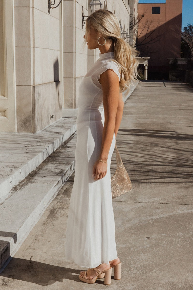 Full body side view of model wearing the Chloe Ivory Mesh Lined Maxi Dress which features white mesh fabric, white lining, maxi length, a high neckline, and short sleeves.