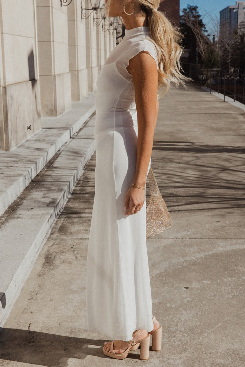 Full body side view of model wearing the Chloe Ivory Mesh Lined Maxi Dress which features white mesh fabric, white lining, maxi length, a high neckline, and short sleeves.