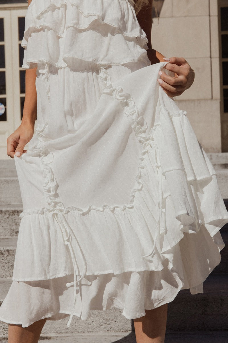 Front view of model wearing the Isla Off White Ruffle Midi Skirt which features off white textured knit fabric, tiered design, tie details, ruffle details, midi length, white lining and elastic waistband.