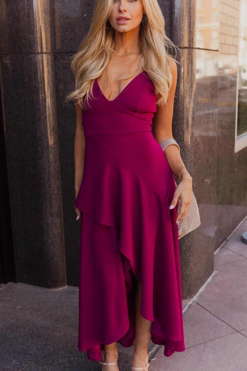 Front view of model wearing the Valerie Magenta Sleeveless Ruffle Midi Dress which features magenta knit fabric, a ruffle hem, a front slit, a v neckline, adjustable spaghetti straps, and a monochromatic back zipper with a hook closure.