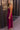 Full body side view of model wearing the Valerie Magenta Sleeveless Ruffle Midi Dress which features magenta knit fabric, a ruffle hem, a front slit, a v neckline, adjustable spaghetti straps, and a monochromatic back zipper with a hook closure.