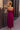 Full body back view of model wearing the Valerie Magenta Sleeveless Ruffle Midi Dress which features magenta knit fabric, a ruffle hem, a front slit, a v neckline, adjustable spaghetti straps, and a monochromatic back zipper with a hook closure.