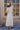 Full body back view of model while wearing the Camila Cream Satin Short Hair Bow that has short cream satin fabric shaped as a bow and a clasp closure.