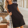 Full body view of model wearing the Palmer Black Short Sleeve Dress which features light taupe knit fabric with a monochrome block stripe design, mini length, two slit side pockets, a left front chest pocket, a round neckline and sleeveless.
