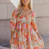 Front view of model wearing the Eloise Multi-Color Swirl Print Mini Dress that has blush, orange, peach, pink, beige, rust and sage fabric, a swirl pattern, two tiered body, mini length, a v-neck, a smocked back and half sleeves with elastic trim.

