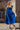 Full body front view of model wearing the Kristina Royal Blue Smocked Sleeveless Midi Dress that has royal blue fabric, side slit pockets, midi length, smocked upper, a scoop neckline, and ruffled straps.