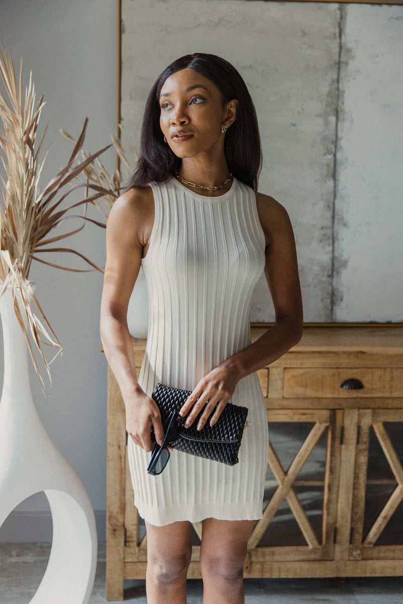 Front view of model wearing the Keep It Classic Dress that has cream knit fabric with a thick ribbing design, mini length, a round neckline, and a sleeveless design.
