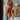 Full body front view of model wearing the Falling For You Dress that has burnt orange fabric, mini length, burnt orange lining, a flare skirt with a tiered ruffle design, a square neckline, thick straps, and a monochromatic back zipper