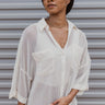 Front view of model wearing the Take A Chance Top that has cream open-knit fabric, monochromatic buttons, two front chest pockets, a collared neckline, and short folded sleeves.