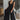 Full body view of model wearing the Moment In Time Jumpsuit in Black which features black lightweight fabric, black lining, wide leg pants, criss cross detail at waist, a plunge neckline, ruffle straps, corset ties in the back, an open back and a monochro