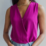 Front view of model wearing the I Fell For You Bodysuit which features purple lightweight fabric, a surplice neckline with a snap closure, a sleeveless design, and a thong bottom with snap closures.