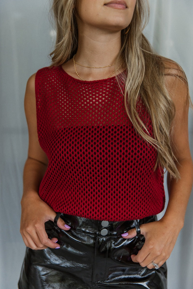 Front close up view of model wearing the Waiting For You Tank which features burgundy open knit fabric, thick hem, round neckline and sleeveless.