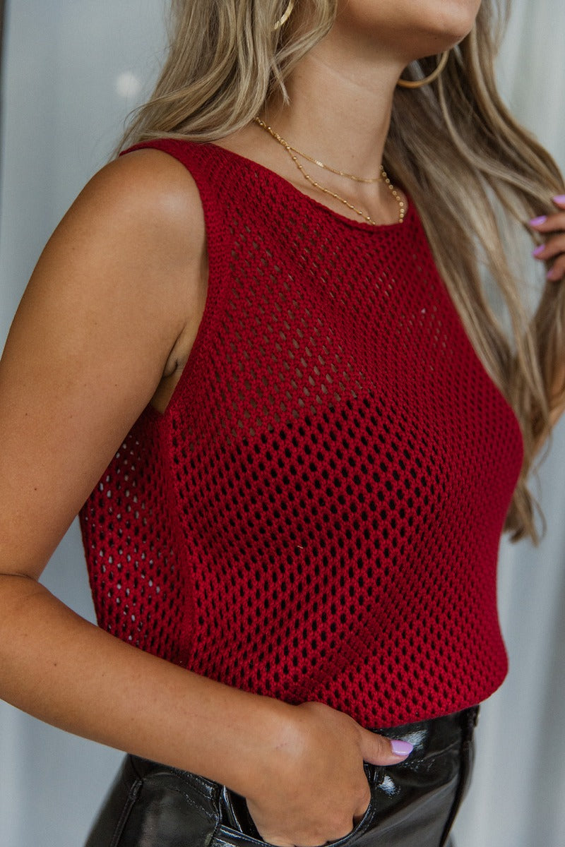 Side view of model wearing the Waiting For You Tank which features burgundy open knit fabric, thick hem, round neckline and sleeveless.