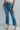 Front view of model wearing the Ceros: Break Even Jeans which features medium blue washed denim, a front zipper with a button closure, belt loops, a high-rise waist, two front pockets, two back pockets, brown stitching and cropped flares.
