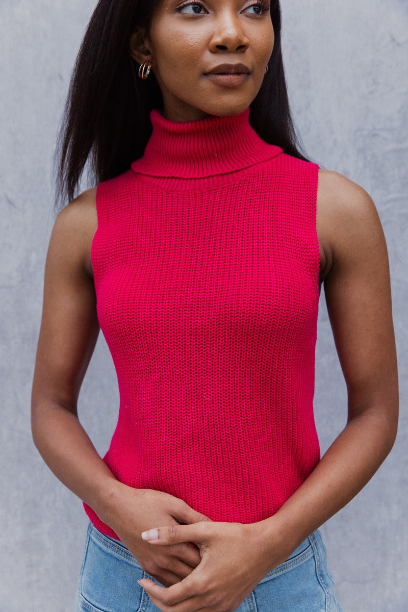 Close up view of model wearing the Rule The World Tank in Pink which features hot pink cable knit fabric, a turtle neck neckline and a sleeveless design.