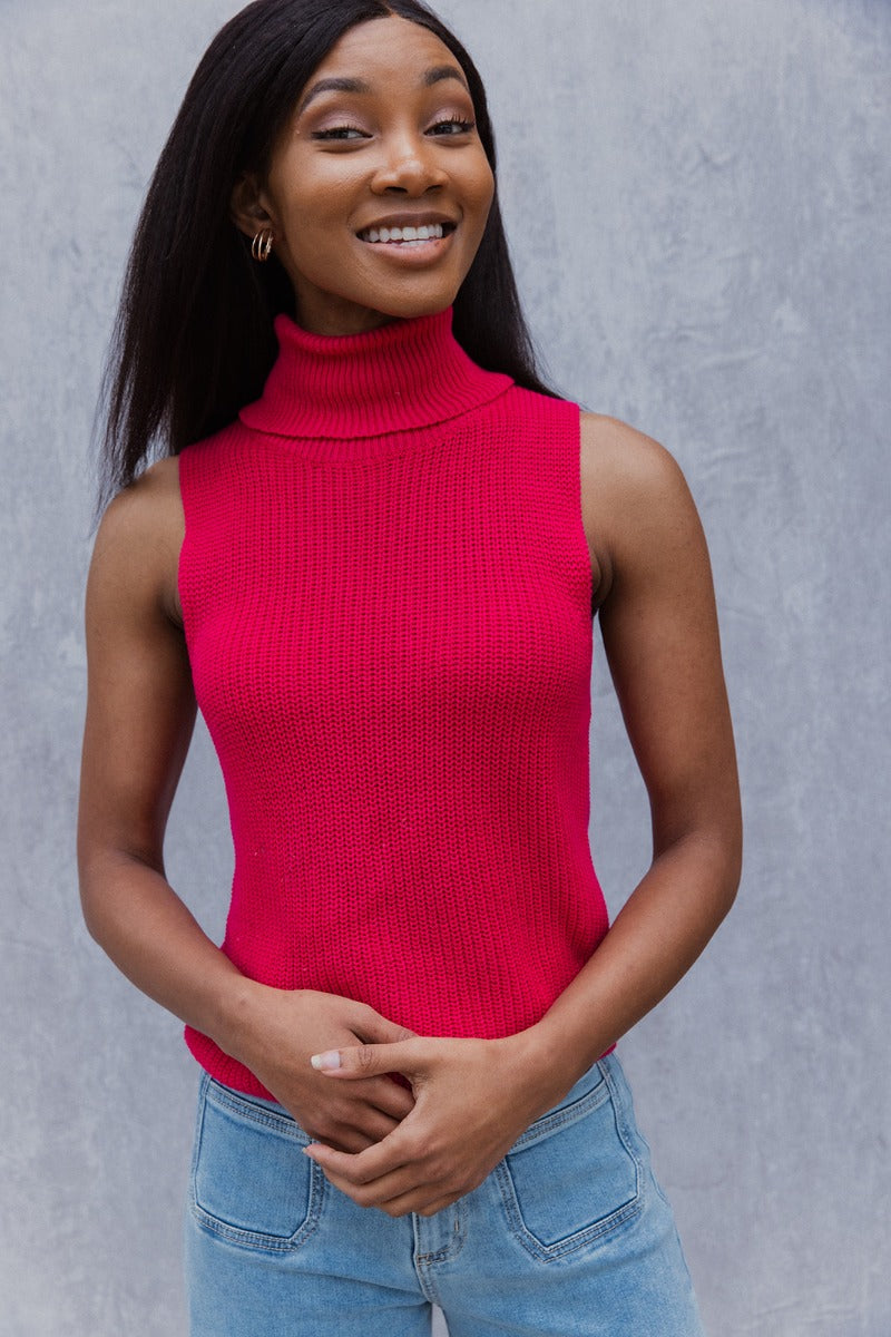 Front view of model wearing the Rule The World Tank in Pink which features hot pink cable knit fabric, a turtle neck neckline and a sleeveless design.