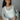 Front view of model wearing the Never Better Open-Knit Sweater that has sage open knit fabric, slits on each side, a round neckline, dropped shoulders, and long flare sleeves