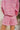 Close-up back view of model wearing the Live Your Best Life Cropped Blazer, which has a pink tweed material, a collar neck, a cuffed long sleeve with a button detail, a button-up front, two front pockets, and a cropped fit